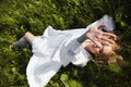 Girl in a long white dress lies on the grass in a field. Blonde woman in the sun in a light dress. Girl resting and dreaming, Royalty Free Stock Photo