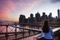 Girl look at Manhattan buildings from Brooklin Bridge at dawn