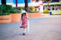 Girl looked down at the ground. Child holds white umbrella that is folded away.