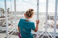 Girl looking through the airport window at vacation destination, excited about the sea and the beach. Royalty Free Stock Photo