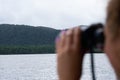 Girl looking through binoculars on forest river