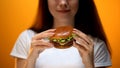 Girl looking at burger, enjoying fast food, high calorie nutrition, obesity risk Royalty Free Stock Photo