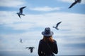 Girl looking at the calm sea on the with wind in her hair and seagulls on the background