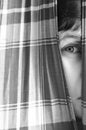 Girl looking through a in curtains