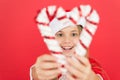 Girl looking through crossed candy canes close up defocused. Christmas decorating ideas. Child Santa Claus costume hold