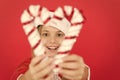 Girl looking through crossed candy canes close up defocused. Christmas decorating ideas. Child Santa Claus costume hold