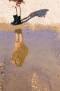 Girl looking at herself reflection puddle pink dress boots.