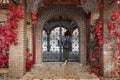 Girl looking inside from Decorative arched iron gateway through brick door