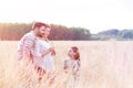 Girl looking at loving parents standing in wheat farm