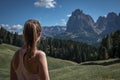 Girl looking at meadows at Alpe di Siusi during summer with view to mountains of Plattkofel and Langkofel in the Dolomite Alps Royalty Free Stock Photo