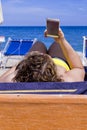 Girl looking at mobile smart phone on a beach with sea on the background. for relaxation and communication concept