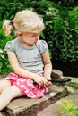 Girl looking at plants grass through magnifying glass.