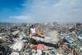 Girl looking a side among mountains of trash at garbage dump