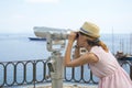 Girl looking thru public binoculars at the seaside wearing straw Royalty Free Stock Photo