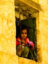 Girl looking to the street behind window, Mahwit. Yemen