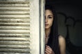 Girl looking through a window shutter