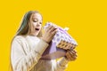 The girl looks delightedly at the gift box on a yellow background. Amazing reaction. Christmas presents Royalty Free Stock Photo