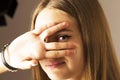 Girl looks through the fingers of her hand. Studio portrait of a very beautiful young girl. Concept: voyeurism, peeping, I`m