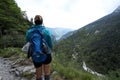 A girl looks at Lake Molveno on the horizon on an alpine path. Taking a break from a hike.