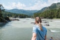 girl looks at a mountain river. girl stands with her back. Mountain landscape. feel the freedom. view of the mountains and the