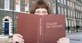 Girl looks over English Dictionary and street Royalty Free Stock Photo