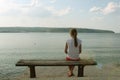 Girl looks at the sea sitting on a bench on the beach