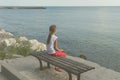 Girl looks at the sea sitting on a bench on the beach Royalty Free Stock Photo