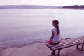 Girl looks at the sea sitting on a bench on the beach Royalty Free Stock Photo