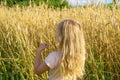 Girl with loose blond hair on the background of a wheat field on a summer farm. Summer, sun and warmth concept Royalty Free Stock Photo