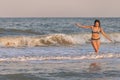 A girl with loose hair walks on the sea with waves and enjoys the sun Royalty Free Stock Photo