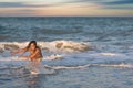 A girl with loose hair walks on the sea with waves and enjoys the sun Royalty Free Stock Photo