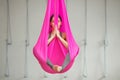 Girl lotus pose aerial antigravity yoga. Woman sits in hammock