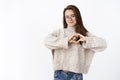 Girl loves cozy sweater in chilly weather. Portrait of sensual and romantic cute young woman in glasses showing heart