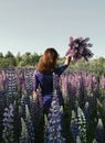 Girl in the lupine field. In blue with a bouquet of lupins