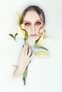 Girl lying in bath with milk and Lily in his hands. Portrait of woman in white water and flowers in hand. Skin rejuvenation, body