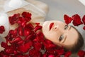 The girl is lying in the bathroom with rose petals. A wellness bath with roses. Royalty Free Stock Photo