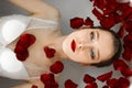 The girl is lying in the bathroom with rose petals. A wellness bath with roses. Royalty Free Stock Photo