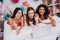 Three Girls Lying on Bed Looking on White Laptop. Royalty Free Stock Photo