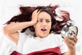 Young girl on a bed looking at the alarm clock Royalty Free Stock Photo