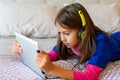 Little girl lying in bed looking at a tablet Royalty Free Stock Photo