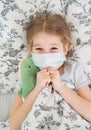 Girl lying in bed in medical mask. dinosaur Royalty Free Stock Photo