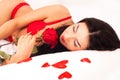 Girl lying in bed, strewn with hearts and roses