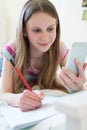 Girl Lying On Bed Using Mobile Phone To Help With Homework Royalty Free Stock Photo
