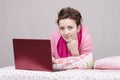 The girl lying in bed works for laptop Royalty Free Stock Photo