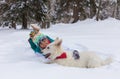 Girl lying down with shepherd dog on the snow, winter time Royalty Free Stock Photo