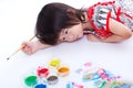 Girl lying on floor and hold paintbrush. On white. Studio shot Royalty Free Stock Photo