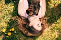 Girl lying on grass with cat on chest. Spring or summer warm weather concept. Bokeh background. Ginger kitten with two face color