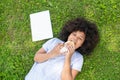 Girl lying on grass and eating fast food in park, happy kid having snack after using laptop outdoor. Royalty Free Stock Photo