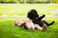 Girl lying on the grass, embracing black puppy Royalty Free Stock Photo