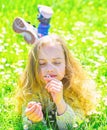 Girl lying on grass, grassplot on background. Girl on dreamy face holds daisy flower. Child enjoy spring sunny weather